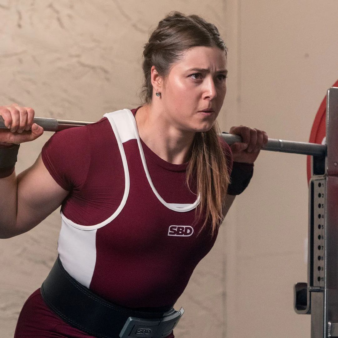 Female athlete about to squat wearing SBD Phoenix Powerlifting Singlet - breathable compression for powerlifting performance - front side view