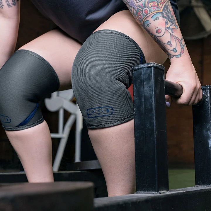 Athlete about to pick up a a farmers carry wearing SBD Storm Weightlifting Knee Sleeves - made in Sheffield, high-grade neoprene for exceptional strength in weightlifting - close side view